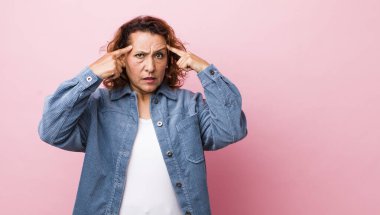 Ciddi ve konsantre bakışları olan orta yaşlı İspanyol bir kadın beyin fırtınası yapıyor ve zorlu bir sorunu düşünüyor.