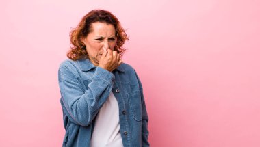 Orta yaşlı İspanyol kadın iğreniyor, kötü ve nahoş bir koku duymamak için burnunu tutuyor.