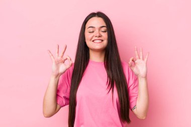 Genç yetişkin bir kadın konsantre olmuş ve meditasyon yapıyor, tatmin olmuş ve rahatlamış hissediyor, düşünüyor ya da bir seçim yapıyor.