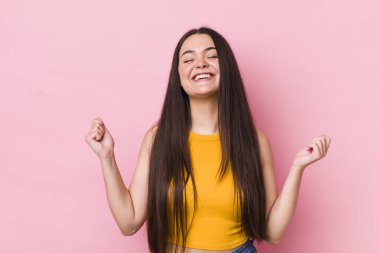 Genç bir kadın son derece mutlu ve şaşırmış görünüyor, başarıyı kutluyor, bağırıyor ve zıplıyor.