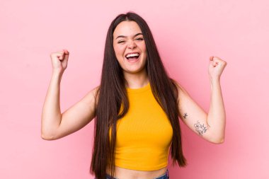 Genç bir kadın mutlu, şaşırmış ve gururlu hissediyor, bağırıyor ve başarıyı büyük bir gülümsemeyle kutluyor.