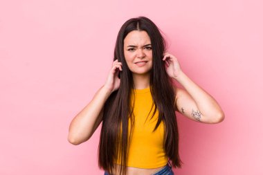 Genç bir kadın sinirli, stresli ve sinirli görünüyor, iki kulağını da sağır edici bir ses, ses ya da yüksek sesle kapatıyor.