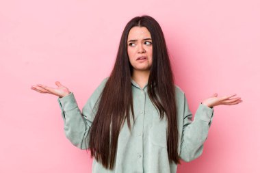 young adult woman shrugging with a dumb, crazy, confused, puzzled expression, feeling annoyed and clueless