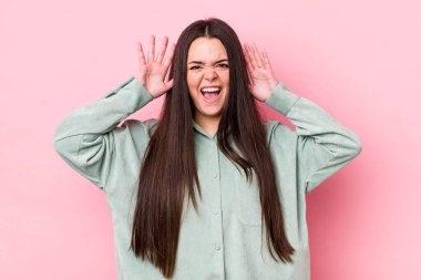 Genç yetişkin bir kadın panik ya da öfke içinde bağırıyor, şok olmuş, korkmuş ya da öfkeli, elleri başının yanında.