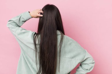 Genç bir kadın bilgisiz ve kafası karışık hissediyor, bir çözüm düşünüyor, eli kalçasında, diğeri kafasında, dikiz aynasından.