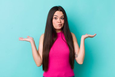 Genç kadın şaşkın ve şaşkın hissediyor, şüpheci, farklı seçenekleri tartıyor ya da komik bir ifadeyle seçiyor.