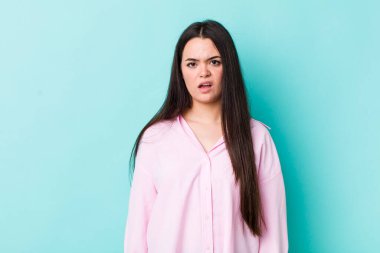 young adult woman feeling puzzled and confused, with a dumb, stunned expression looking at something unexpected