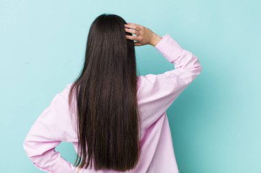 Genç bir kadın bilgisiz ve kafası karışık hissediyor, bir çözüm düşünüyor, eli kalçasında, diğeri kafasında, dikiz aynasından.