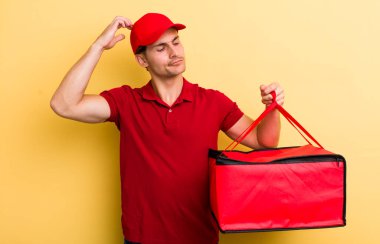 Kafası karışmış, kafası karışmış, kaşınan genç yakışıklı bir adam. Pizza teslimatı kavramı