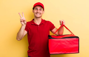 Genç yakışıklı adam gülümsüyor ve mutlu görünüyor, zafer ya da barış işareti yapıyor. Pizza teslimatı kavramı