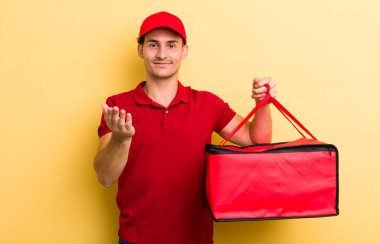 Genç yakışıklı adam mutlu bir şekilde gülümsüyor ve bir konsept sunuyor. Pizza teslimatı kavramı