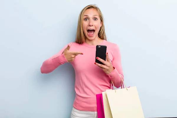 若い大人のブロンドの女性は興奮して驚いてる ショッピングバッグのコンセプト — ストック写真