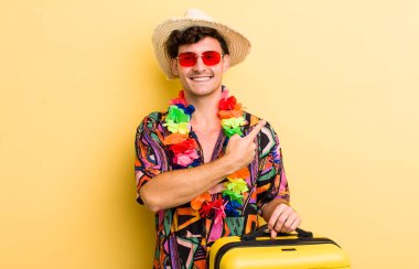 Genç yakışıklı adam neşeyle gülümsüyor, mutlu hissediyor ve bir tarafı işaret ediyor. Yaz tatili konsepti