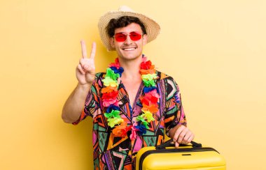 Genç yakışıklı adam gülümsüyor ve arkadaş canlısı görünüyor, iki numarayı gösteriyor. Yaz tatili konsepti