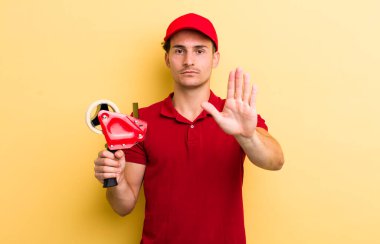 Genç ve yakışıklı adam ciddi görünüyor. Avuç içi gösteriyor. Durma hareketi yapıyor. Packer employee kavramı