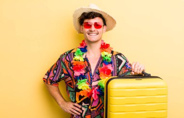 Genç yakışıklı adam mutlu bir şekilde gülümsüyor, eli kalçasında ve kendinden emin. Yaz tatili konsepti