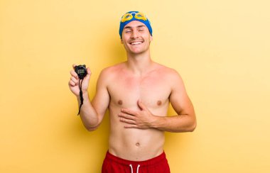 Genç yakışıklı adam komik bir şakaya yüksek sesle gülüyor. yüzücü kavramı