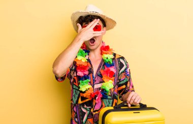 Genç, yakışıklı adam şok olmuş, korkmuş ya da korkmuş görünüyor, yüzünü eliyle kapatıyor. Yaz tatili konsepti