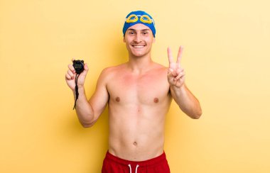 Genç yakışıklı adam gülümsüyor ve mutlu görünüyor, zafer ya da barış işareti yapıyor. yüzücü kavramı