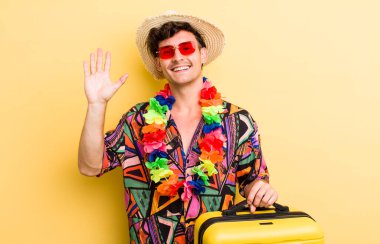 Genç yakışıklı adam mutlu bir şekilde gülümsüyor, el sallıyor, hoş geldin diyor ve seni selamlıyor. Yaz tatili konsepti