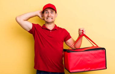 Genç ve yakışıklı adam stresli, endişeli ya da korkmuş, elleri başının üstünde. Pizza teslimatı kavramı