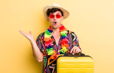 Genç, yakışıklı adam şaşırmış ve şok olmuş görünüyor. Çenesi düşmüş, elinde bir nesne var. Yaz tatili konsepti