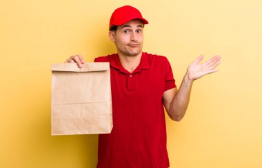 Genç yakışıklı adam şaşkın, şaşkın ve şüpheci hissediyor. teslimat ve paket konsepti