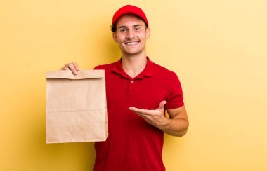 Genç yakışıklı adam neşeyle gülümsüyor, mutlu hissediyor ve bir konsept gösteriyor. teslimat ve paket konsepti