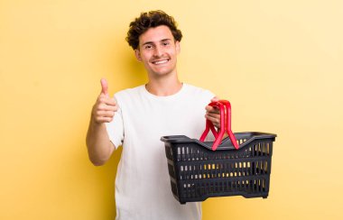 Genç yakışıklı adam gururlu, olumlu gülümsüyor. boş alışveriş sepeti kavramı