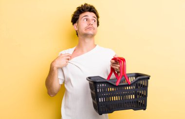 Genç yakışıklı, stresli, endişeli, yorgun ve hayal kırıklığına uğramış hissediyor. boş alışveriş sepeti kavramı