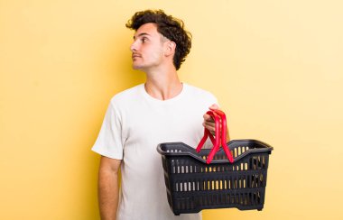 Profil görünümlü genç adam hayal mi kuruyor yoksa hayal mi kuruyor? boş alışveriş sepeti kavramı