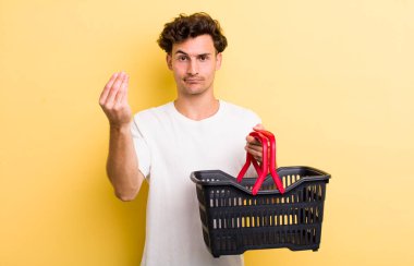 Genç yakışıklı adam kapiş ya da para hareketi yapıyor, sana ödemeni söylüyor. boş alışveriş sepeti kavramı