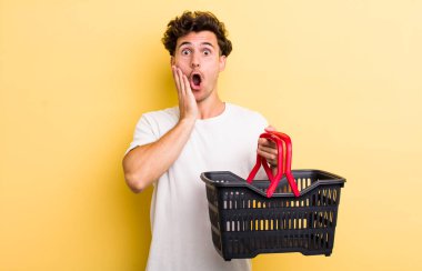 Genç ve yakışıklı adam şok olmuş ve korkmuş hissediyor. boş alışveriş sepeti kavramı