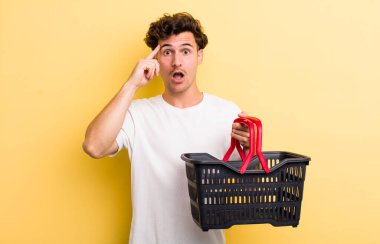 Genç yakışıklı adam şaşırmış görünüyor, yeni bir düşünce, fikir ya da konsept fark ediyor. boş alışveriş sepeti kavramı