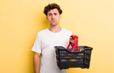 Genç yakışıklı üzgün ve ağlayan mutsuz bakışlı bir adam. boş alışveriş sepeti kavramı