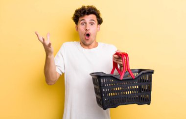 Genç ve yakışıklı adam şok olmuş ve şaşırmış hissediyor. boş alışveriş sepeti kavramı