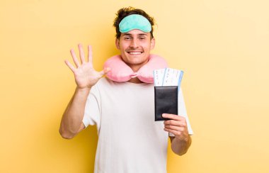 Genç yakışıklı adam gülümsüyor ve arkadaş canlısı görünüyor, beş numarayı gösteriyor. uçuş yolcu kavramı