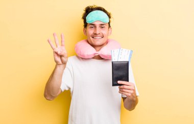 Genç yakışıklı adam gülümsüyor ve arkadaş canlısı görünüyor, üç numarayı gösteriyor. uçuş yolcu kavramı