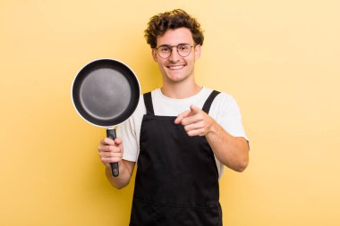 Genç ve yakışıklı bir adam kamerayı işaret ederek seni seçiyor. Şefin tava konsepti.