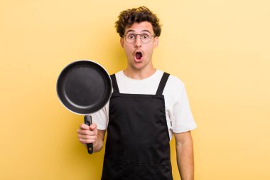 Genç ve yakışıklı adam çok şaşırmış ya da şaşkın görünüyor. Şefin tava konsepti.