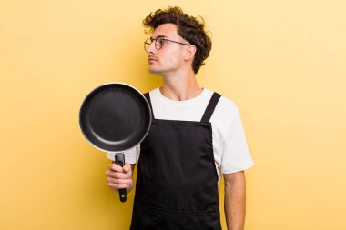 Profil görünümlü genç adam hayal mi kuruyor yoksa hayal mi kuruyor? Şefin tava konsepti.