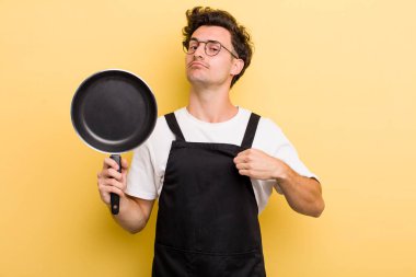 Genç yakışıklı adam kibirli, başarılı, pozitif ve gururlu görünüyor. Şefin tava konsepti.