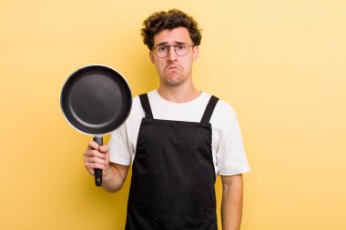 Genç yakışıklı üzgün ve ağlayan mutsuz bakışlı bir adam. Şefin tava konsepti.