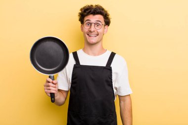 Genç yakışıklı adam mutlu ve hoş bir şekilde şaşırmış görünüyor. Şefin tava konsepti.