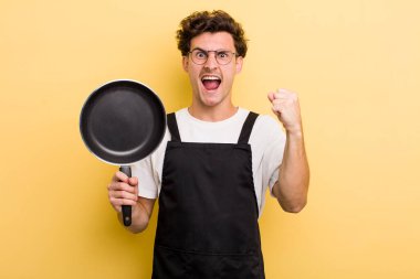 Genç yakışıklı adam sinirli bir ifadeyle agresif bir şekilde bağırıyor. Şefin tava konsepti.