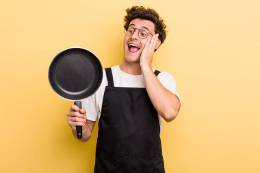 Genç yakışıklı adam mutlu, heyecanlı ve şaşırmış hissediyor. Şefin tava konsepti.