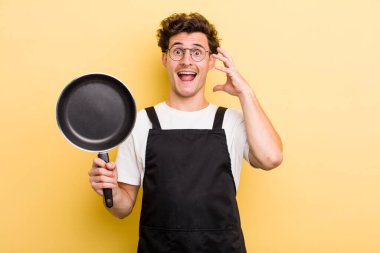 Genç yakışıklı adam ellerini havaya kaldırarak çığlık atıyor. Şefin tava konsepti.