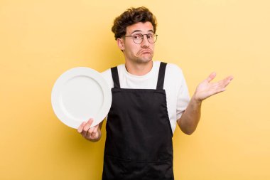 Genç yakışıklı adam şaşkın, şaşkın ve şüpheci hissediyor. boş tabak kavramı