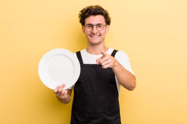 Genç ve yakışıklı bir adam kamerayı işaret ederek seni seçiyor. boş tabak kavramı