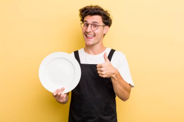 Genç yakışıklı adam gururlu, olumlu gülümsüyor. boş tabak kavramı